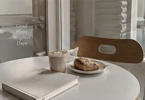 A planner and coffee beside a sunny window