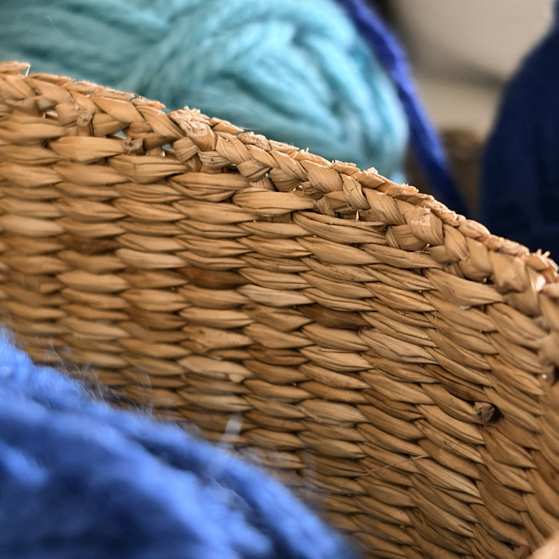 Close-up of a woven basket surrounded by blue and turquoise yarn.