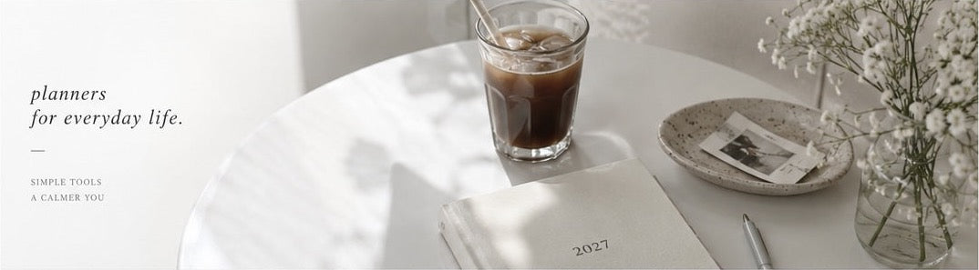 Sunlit table with a planner, iced coffee and flowers