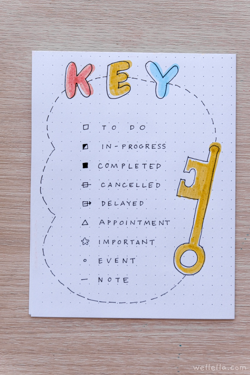 A simple bullet journal key example with the word key written in primary colors and an illustration of an antique golden key.
