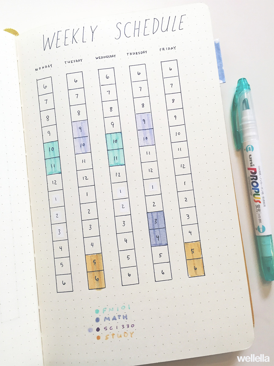 A page in a dot grid notebook with a handwritten weekly times table, with classes blocked out with colorful markers.