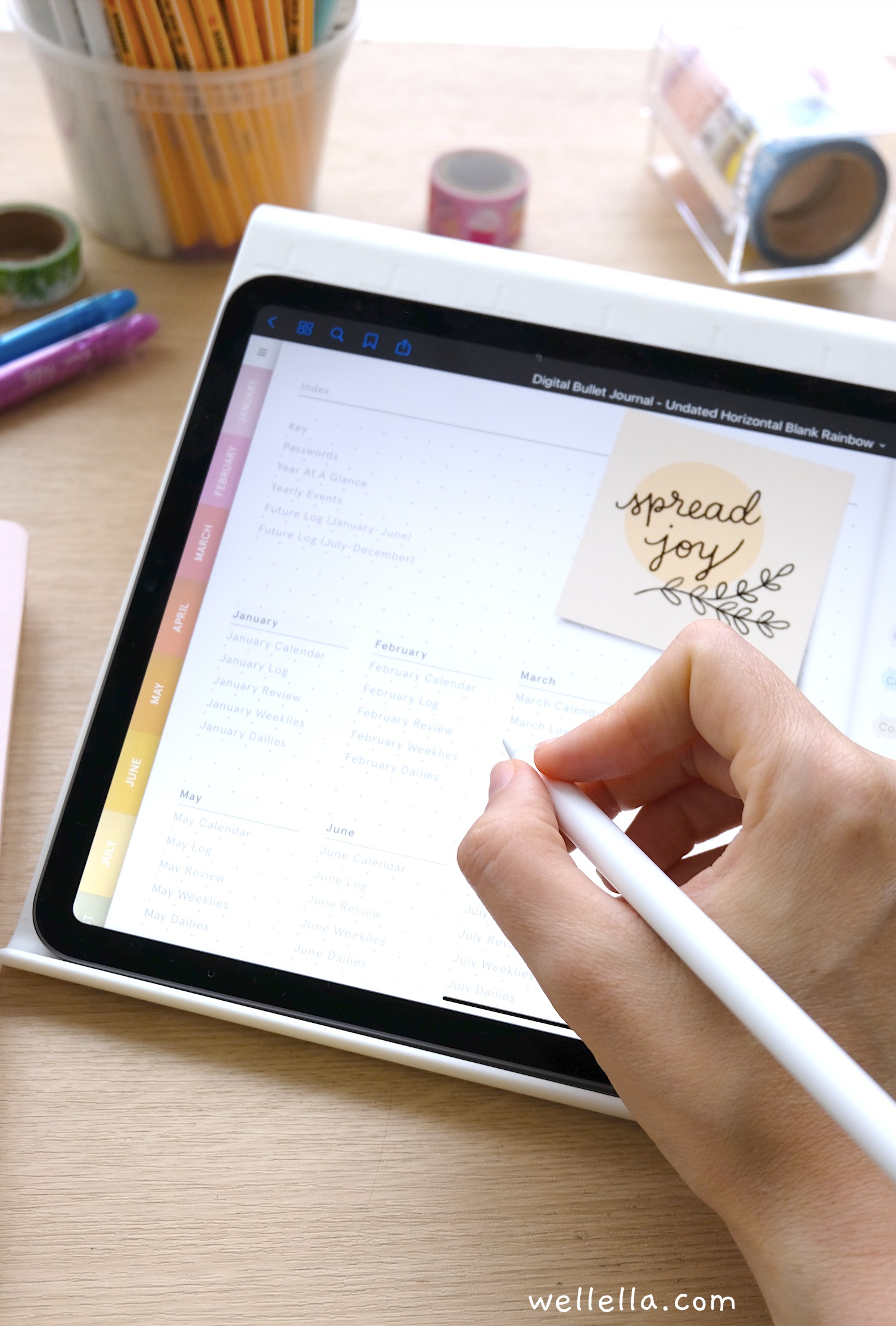 An ipad with a digital bullet journal on a table, as someone writes on the page using an apple pencil.